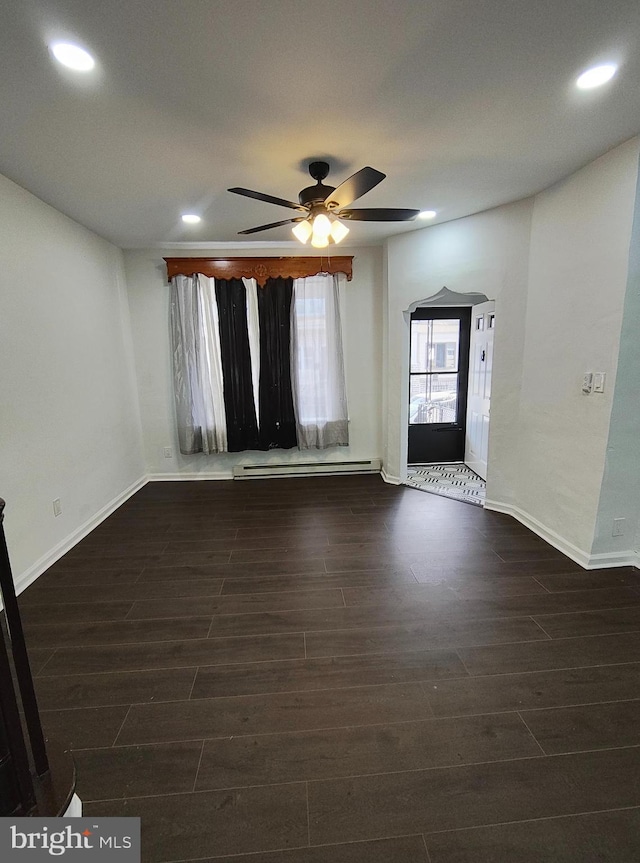 unfurnished room featuring a baseboard heating unit, ceiling fan, and dark wood-type flooring