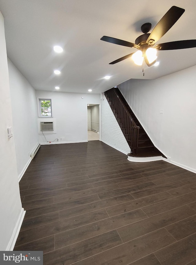 unfurnished living room with dark wood-type flooring, a wall unit AC, ceiling fan, and a baseboard heating unit