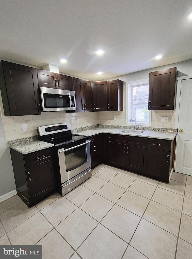 kitchen featuring sink, stainless steel appliances, tasteful backsplash, dark brown cabinets, and light tile patterned floors