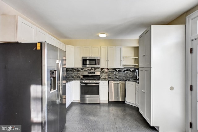 kitchen featuring dark stone counters, white cabinets, sink, tasteful backsplash, and stainless steel appliances