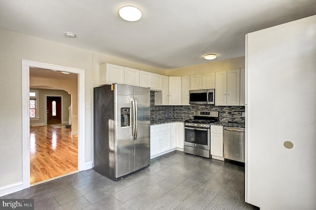 kitchen with white cabinets, decorative backsplash, dark hardwood / wood-style flooring, and stainless steel appliances