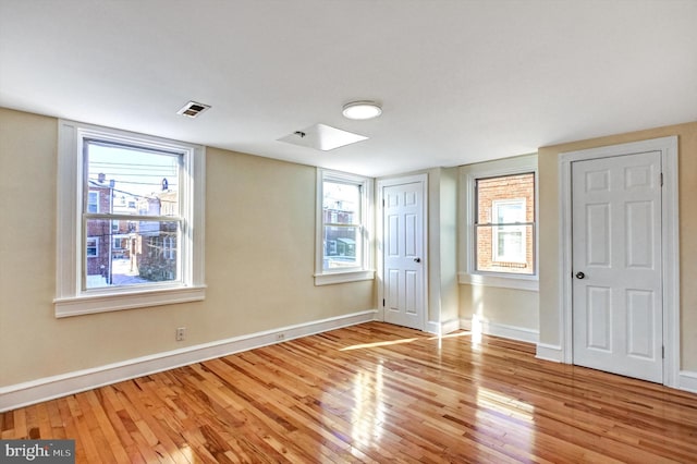 unfurnished bedroom featuring multiple windows and light hardwood / wood-style floors