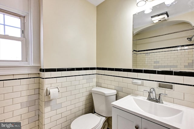 bathroom featuring vanity, toilet, and tile walls