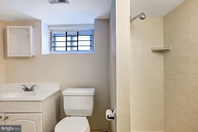 bathroom with vanity, toilet, and tiled shower