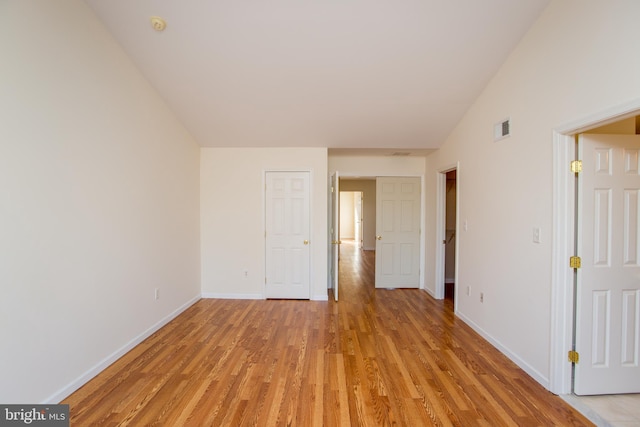 unfurnished room featuring lofted ceiling and light hardwood / wood-style flooring