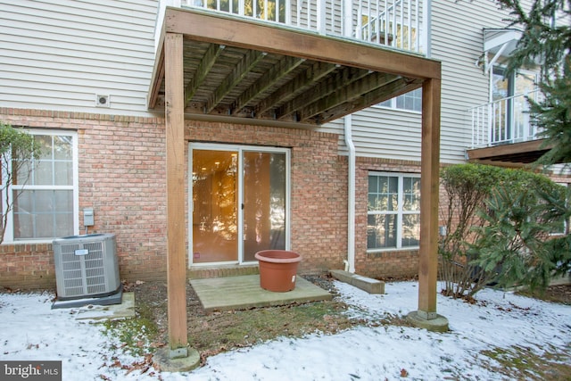 snow covered property entrance with central air condition unit