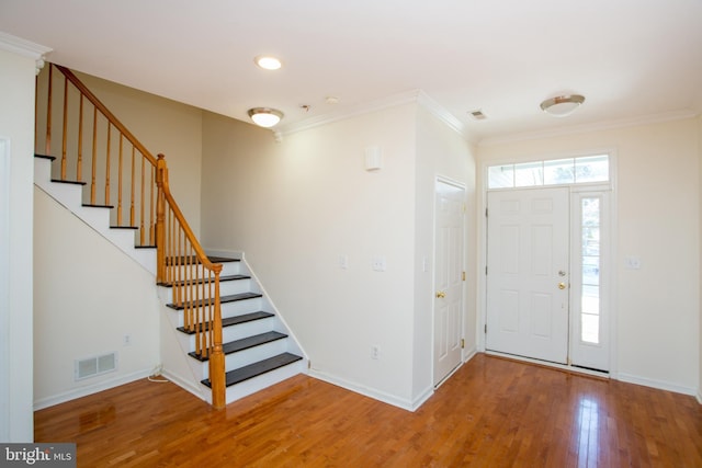 foyer entrance with hardwood / wood-style flooring and crown molding