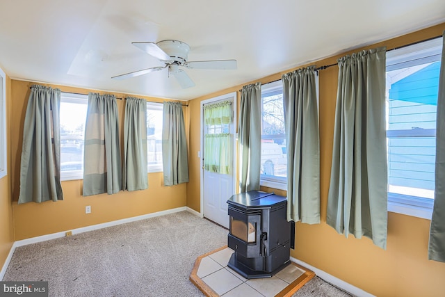 interior space featuring ceiling fan, a wood stove, and light carpet