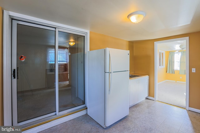 kitchen with white refrigerator and white cabinetry