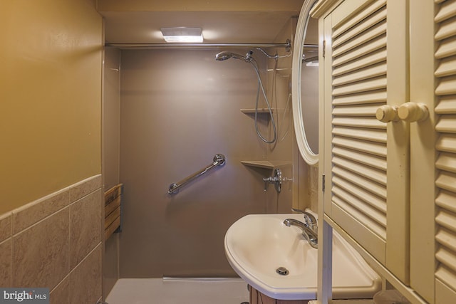 bathroom featuring tile walls, sink, and a shower