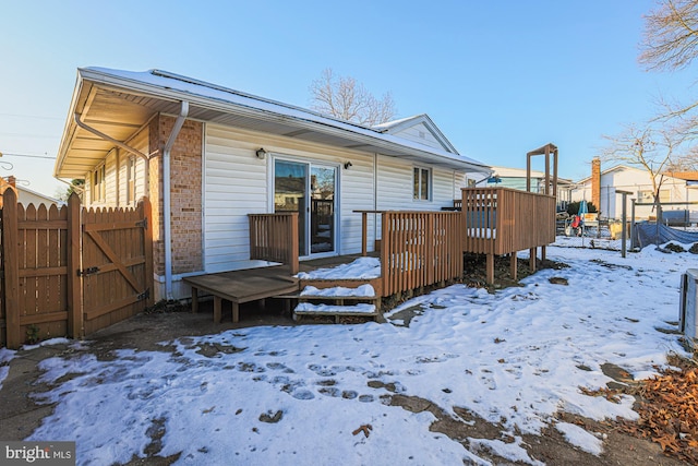 snow covered rear of property featuring a wooden deck