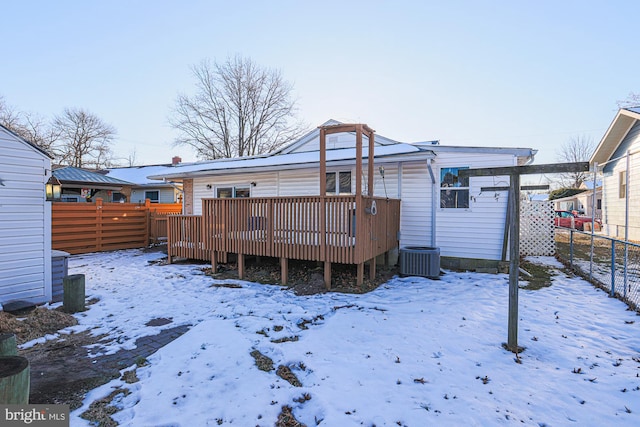 snow covered back of property with central air condition unit and a deck