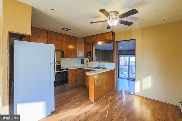 kitchen featuring kitchen peninsula, white fridge, stainless steel range with electric cooktop, light hardwood / wood-style floors, and sink