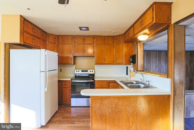 kitchen with white fridge, wood-type flooring, kitchen peninsula, stainless steel electric range oven, and sink