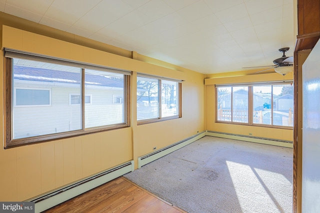 unfurnished sunroom featuring ceiling fan and a baseboard heating unit