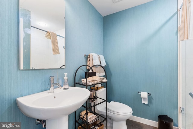 bathroom featuring tile patterned floors, toilet, sink, and walk in shower