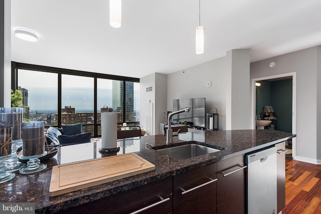 kitchen with sink, hanging light fixtures, expansive windows, stainless steel dishwasher, and dark stone counters