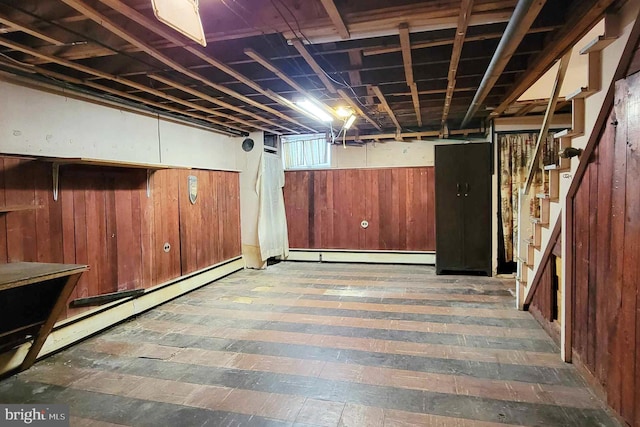 basement featuring a baseboard radiator and wood walls