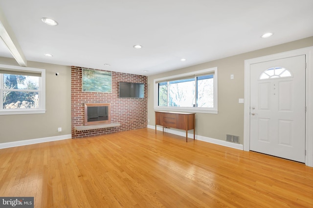 entryway with a fireplace, light wood-type flooring, and a wealth of natural light