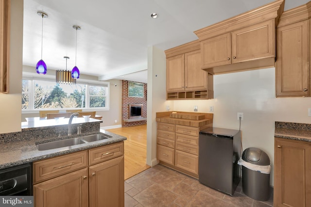 kitchen featuring pendant lighting, dishwasher, sink, a brick fireplace, and fridge