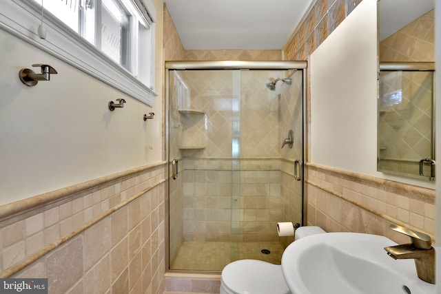 bathroom featuring sink, a shower with shower door, tile walls, and toilet