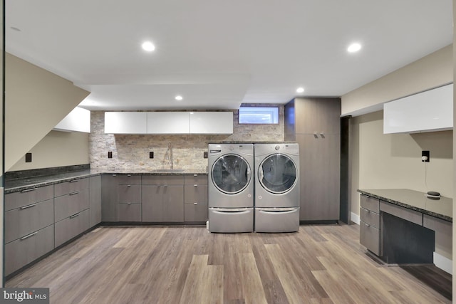 clothes washing area featuring sink, light hardwood / wood-style flooring, and independent washer and dryer