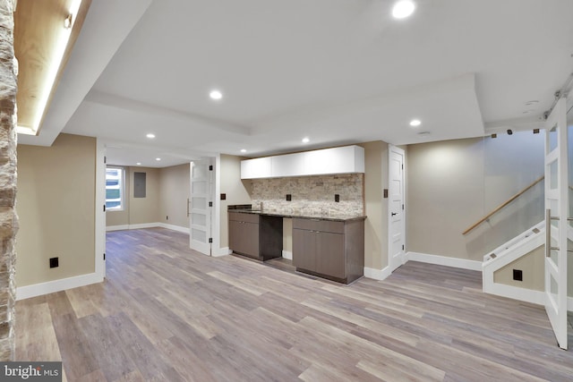 kitchen featuring light hardwood / wood-style floors, light stone counters, and tasteful backsplash