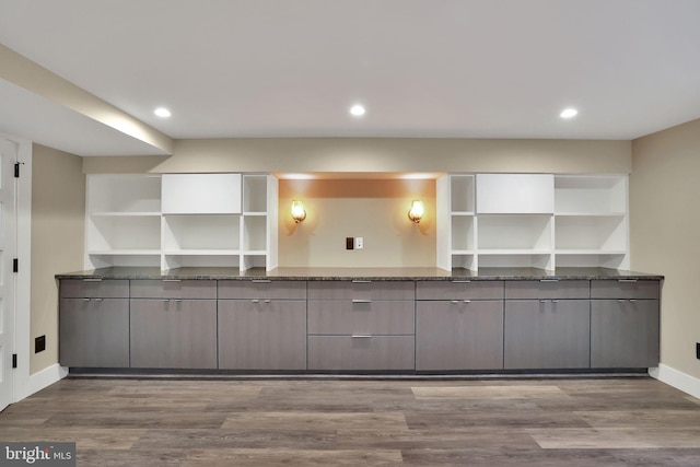 kitchen featuring dark stone countertops, hardwood / wood-style floors, and gray cabinets