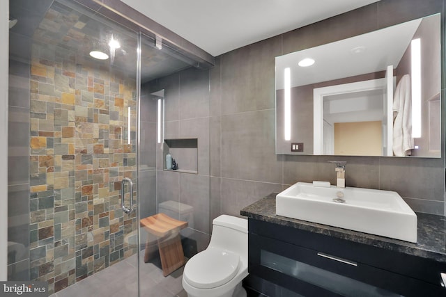 bathroom featuring vanity, tile patterned flooring, toilet, tile walls, and walk in shower