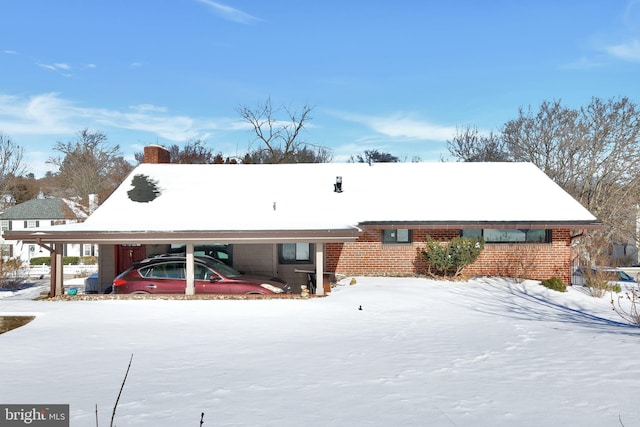 snow covered rear of property featuring a carport