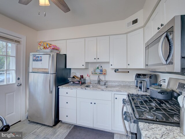 kitchen featuring light stone countertops, ceiling fan, sink, stainless steel appliances, and white cabinets