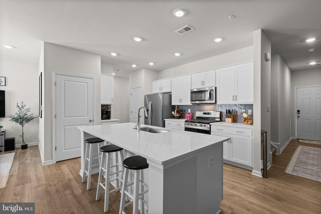 kitchen with white cabinets, stainless steel appliances, and an island with sink