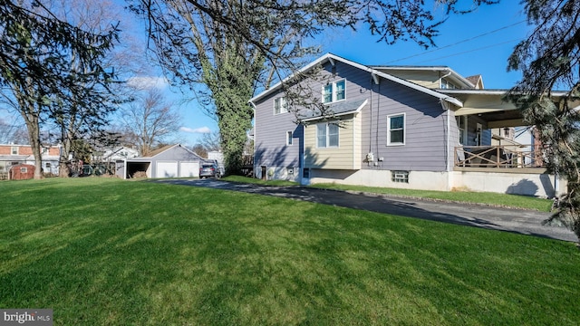 rear view of property featuring a lawn, a garage, and an outbuilding