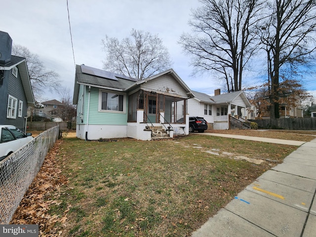 bungalow featuring solar panels, a porch, and a front lawn