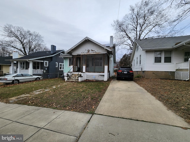 bungalow-style home featuring a sunroom and a front lawn