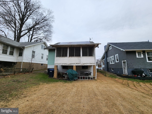 back of property with a lawn and a sunroom