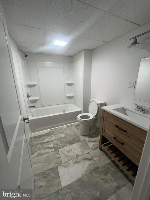 full bathroom with toilet, vanity,  shower combination, and a paneled ceiling