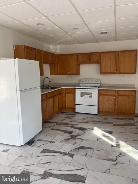 kitchen with sink, white appliances, and a drop ceiling