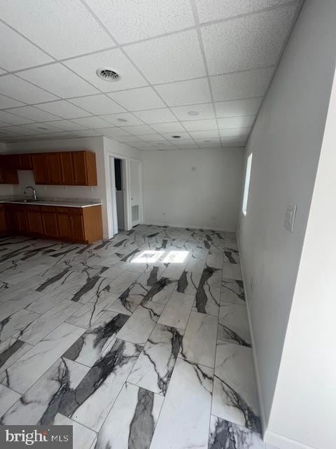 unfurnished living room featuring sink and a drop ceiling