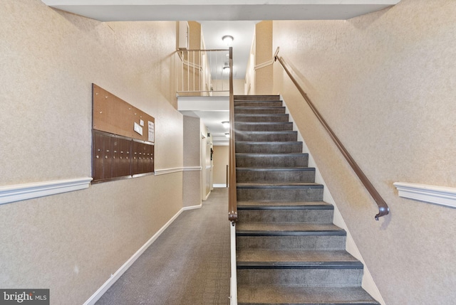 stairs featuring a towering ceiling and mail boxes