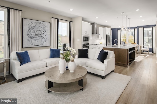 living room featuring light wood-type flooring, sink, and a chandelier