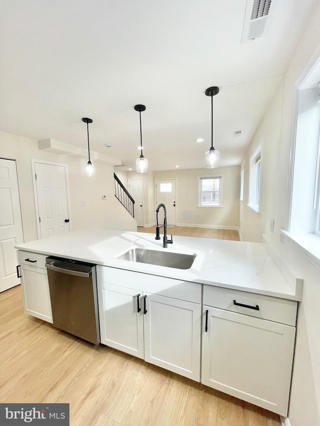 kitchen with pendant lighting, dishwasher, sink, light stone counters, and white cabinetry