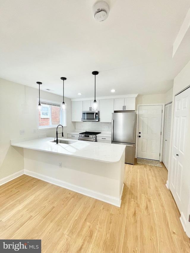 kitchen with appliances with stainless steel finishes, backsplash, sink, decorative light fixtures, and white cabinetry