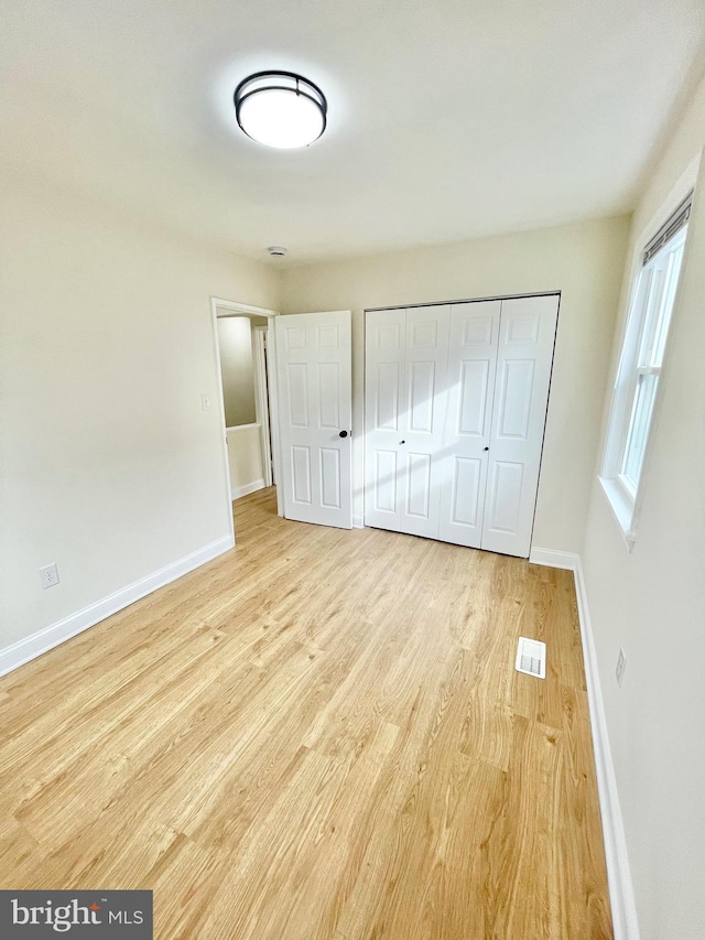 unfurnished bedroom with light hardwood / wood-style flooring and a closet