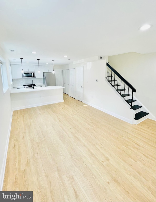 unfurnished living room with sink and light hardwood / wood-style floors