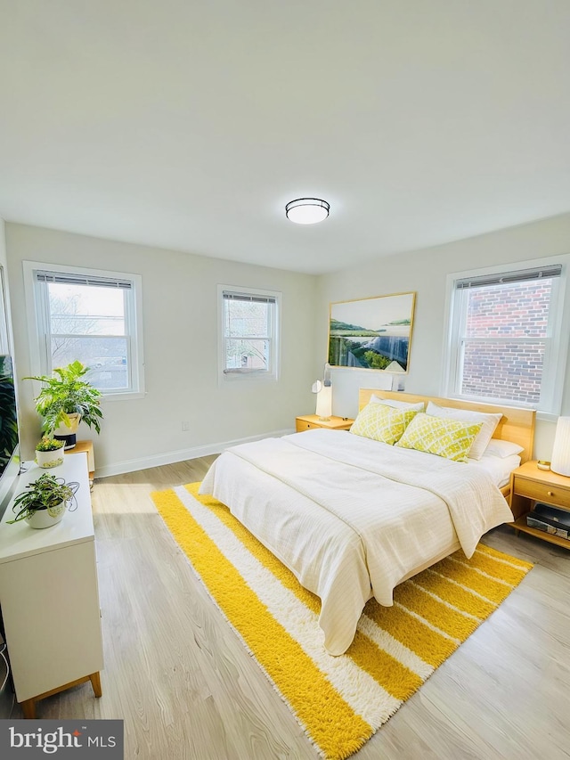 bedroom with multiple windows and light hardwood / wood-style flooring