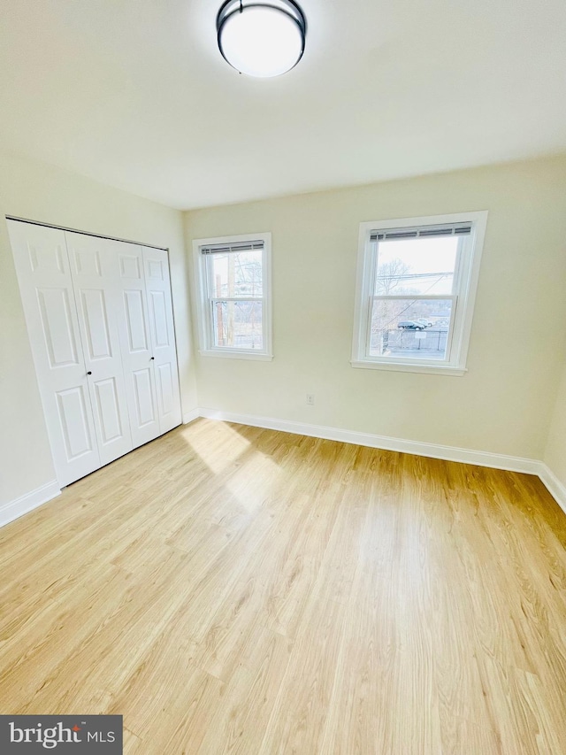 unfurnished bedroom with light wood-type flooring and a closet