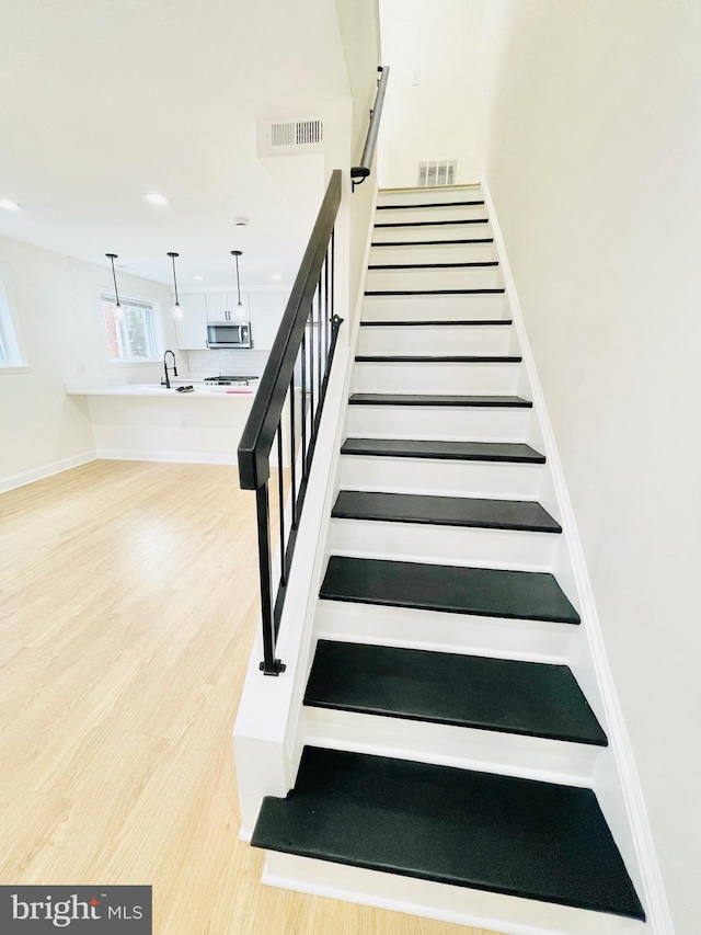 stairway featuring hardwood / wood-style flooring and sink