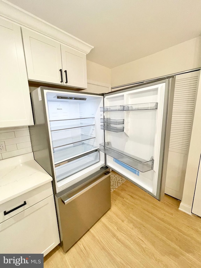 interior space featuring backsplash, built in fridge, light hardwood / wood-style flooring, and white cabinets