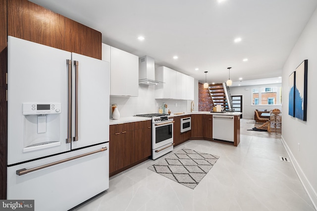 kitchen featuring white appliances, white cabinetry, wall chimney range hood, decorative light fixtures, and tasteful backsplash